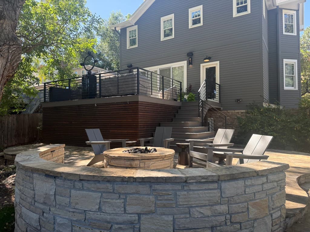 Curved stone seat wall around a fire pit patio below a deck