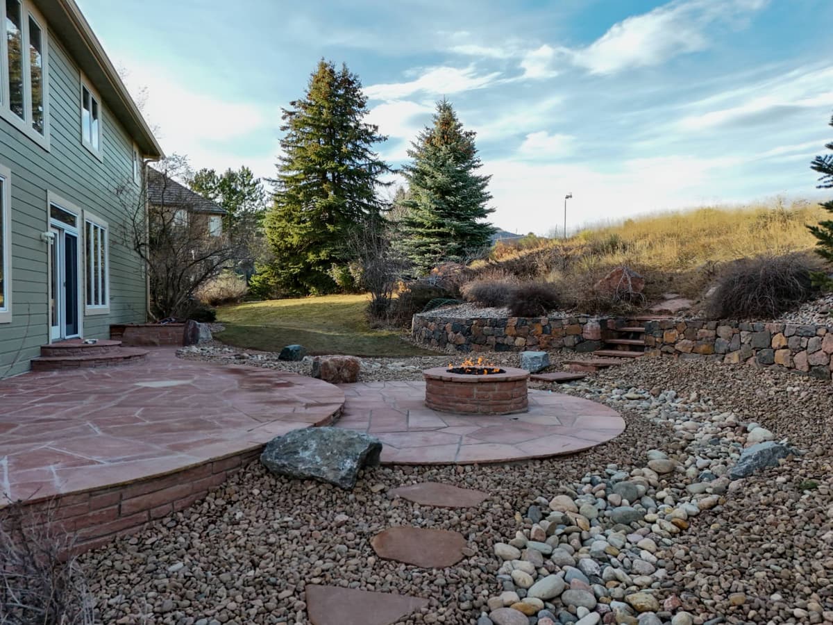 Flagstone patio and gas fire pit surrounded by river rock, boulders and stone walls