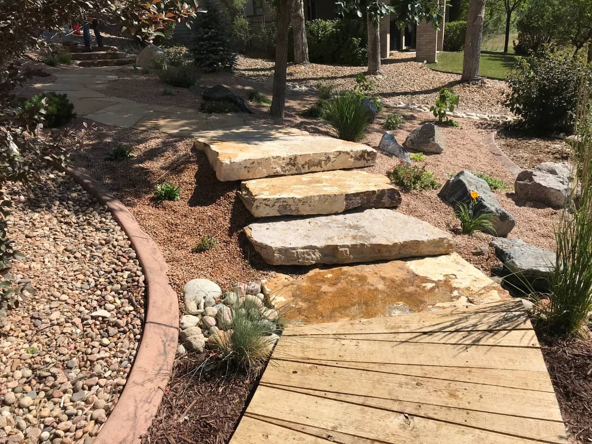 Sandstone slab steps through gravel and river rock with small drought tolerant plants