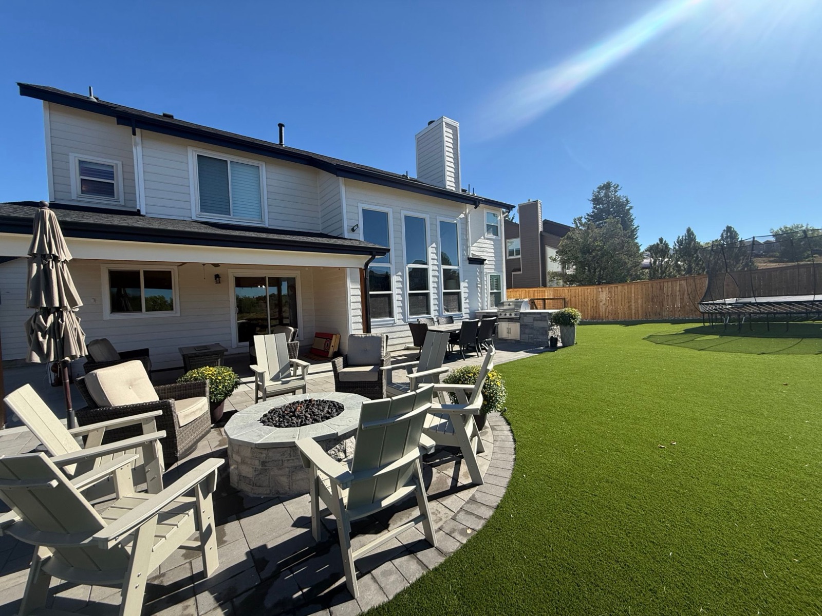 Curved paver patio with a stone fire pit and lounge seating