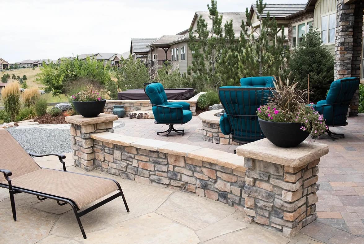 Stacked-stone seat walls and pillar planters around a patio seating area