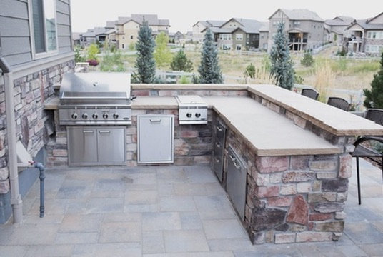 Stone outdoor kitchen with a built-in grill, side burner and bar-height counter