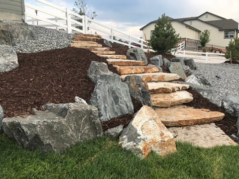 Sandstone slab steps set among boulders on a mulched hillside