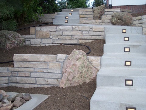 Terraced stone retaining walls and concrete steps with built-in step lights