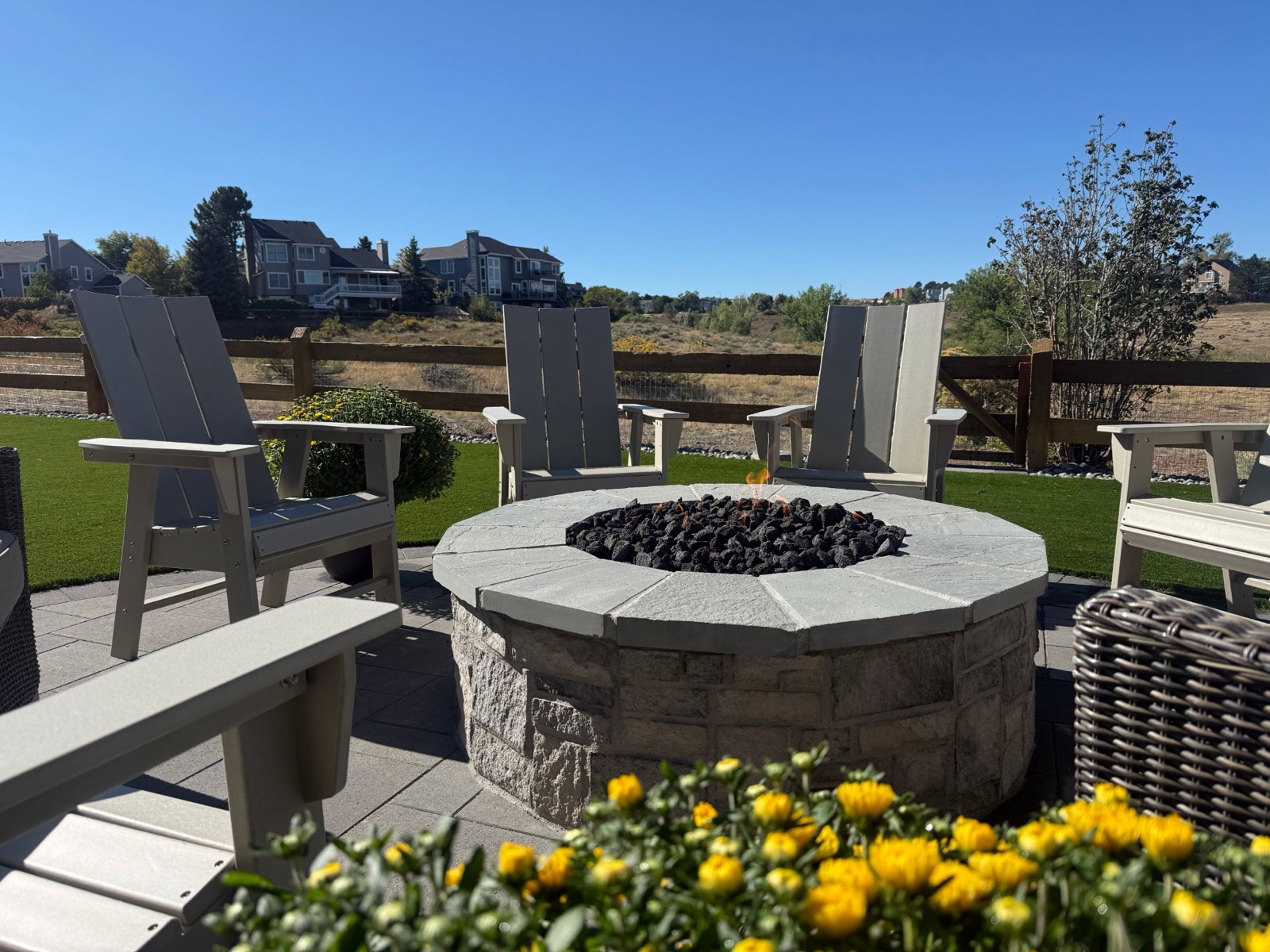 Round stone gas fire pit with Adirondack chairs