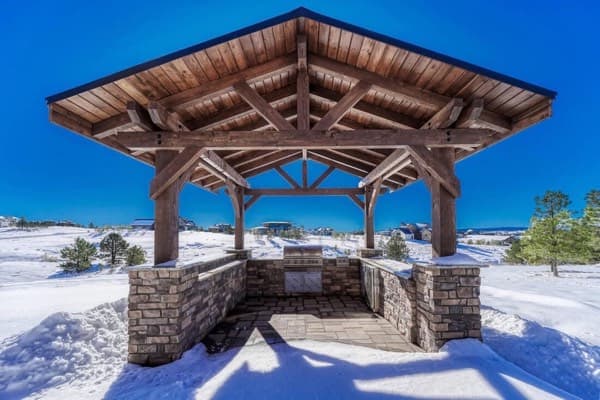 Timber pavilion with stone half walls and a built in grill in winter