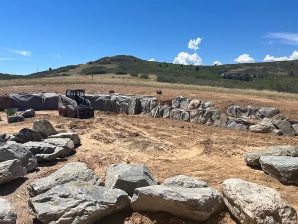 Boulder retaining wall under construction on a hillside site