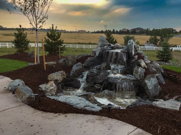 Cascading boulder waterfall beside a lawn