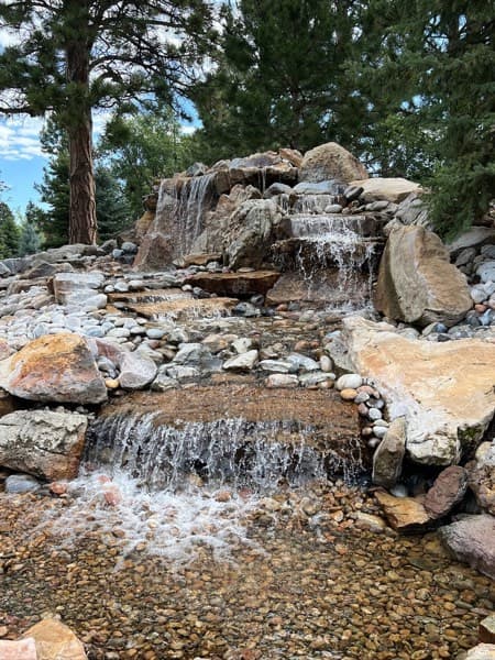 Multi-tier boulder waterfall among pine trees