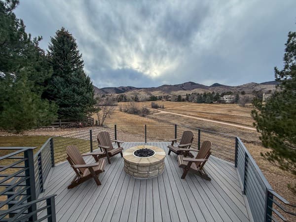 Composite deck with a stone fire pit, Adirondack chairs and foothills views