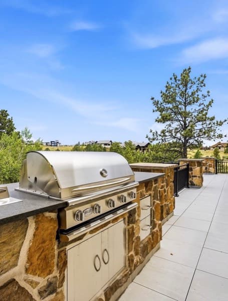 Stone outdoor kitchen with a stainless grill on a large-format paver patio